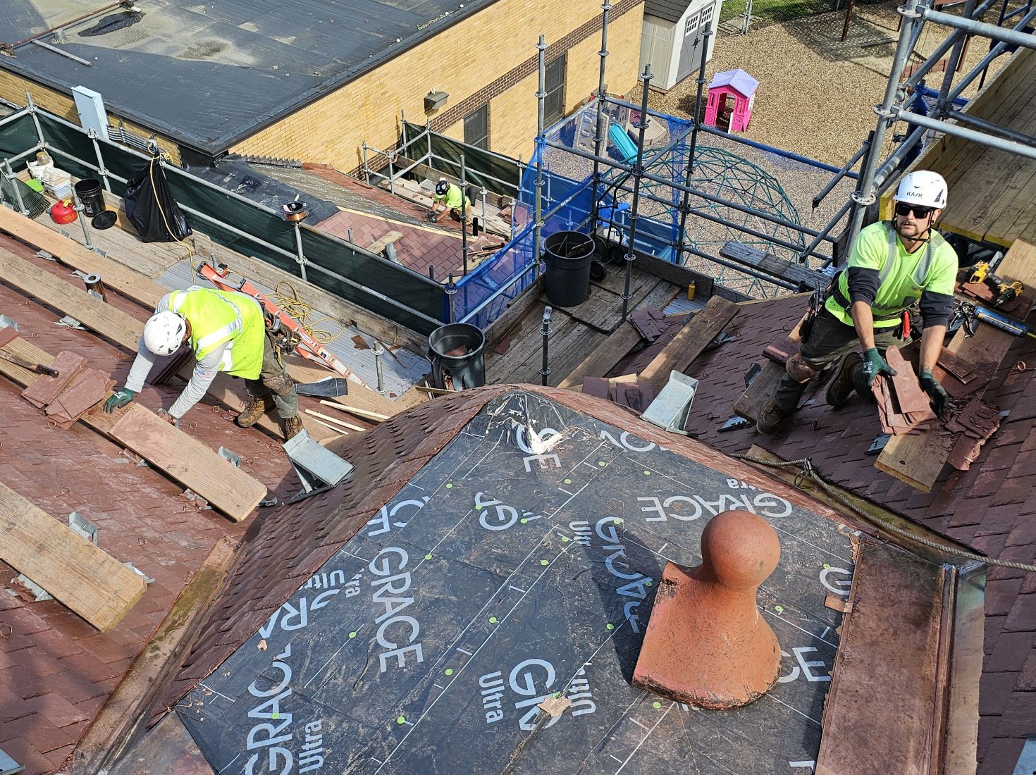 slate roof replacement in progress at a historic Romanesque community center