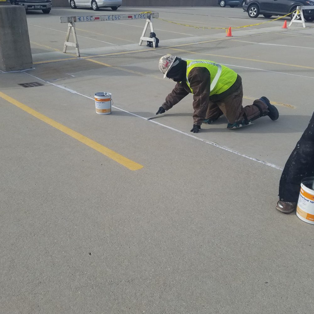 A worker completes sealant application. Restored concrete and newly installed sealant provides durable weather protection.