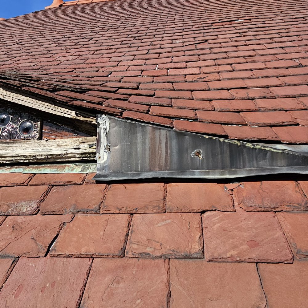 Deteriorated wood decorative window in slate roof