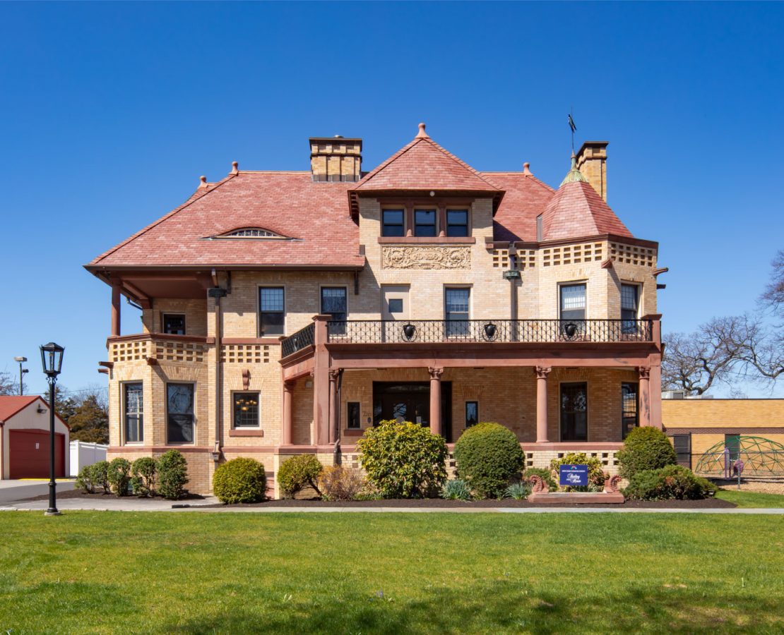 Romanesque building with gabled roofs and wraparound porch