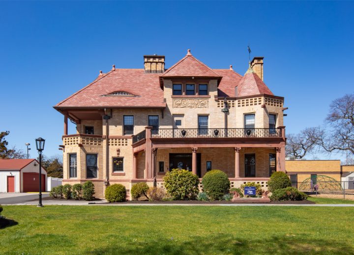 Romanesque building with gabled roofs and wraparound porch