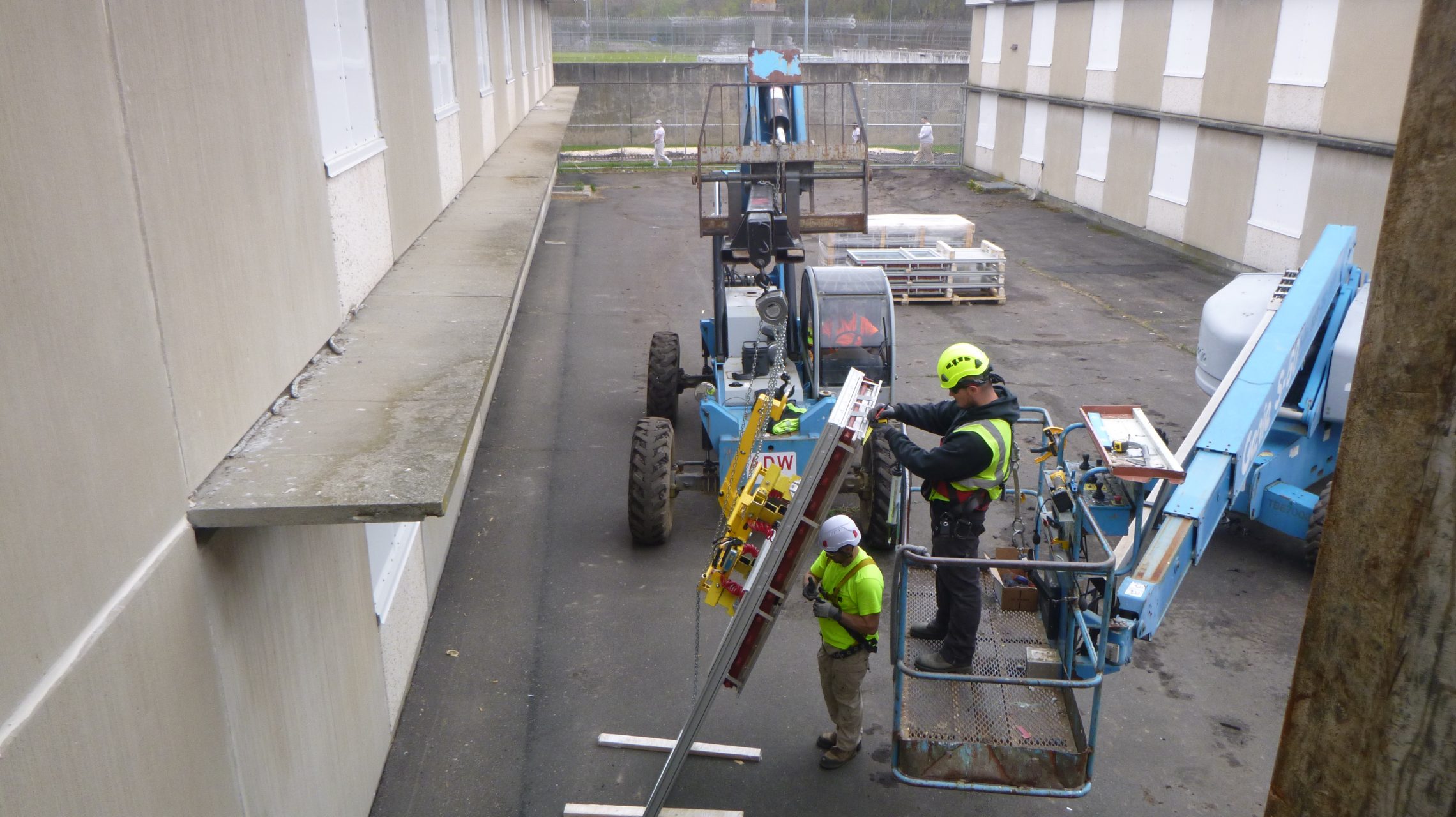 Construction workers prepare to install a large new window at a secure facility.