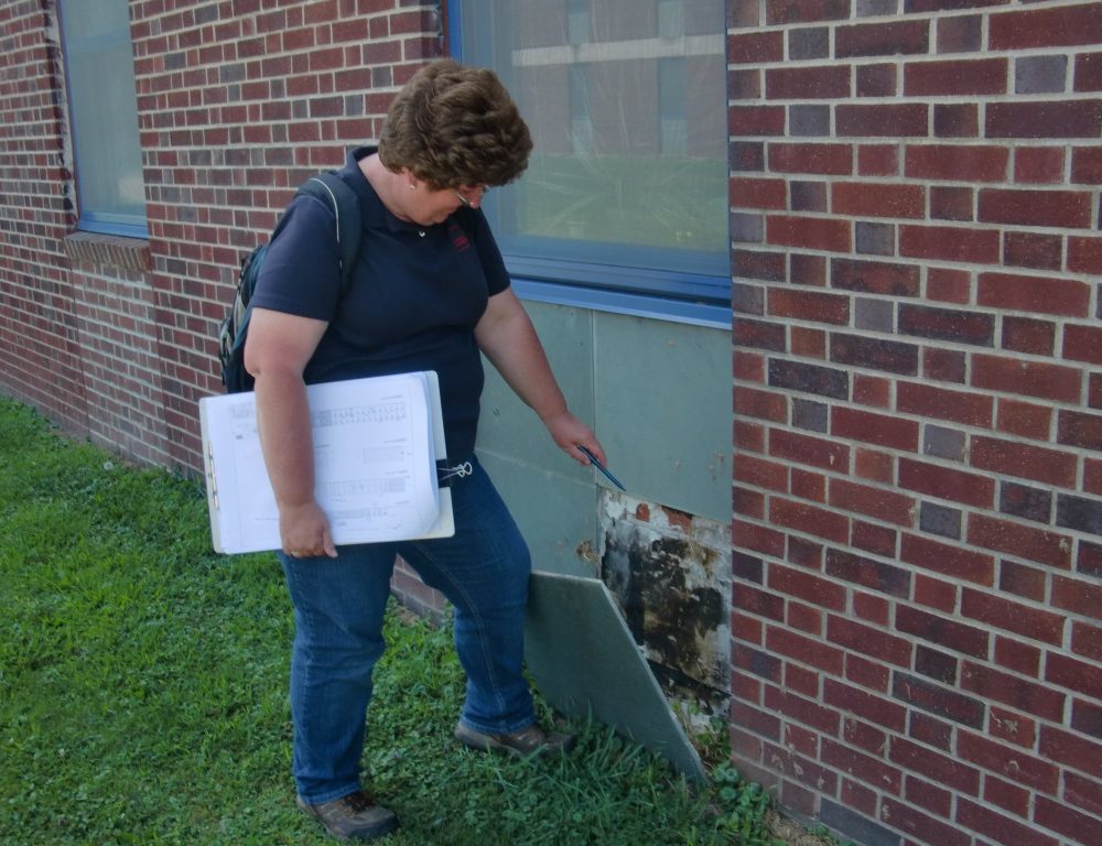 An architect opens an exterior wall panel to assess concealed masonry.
