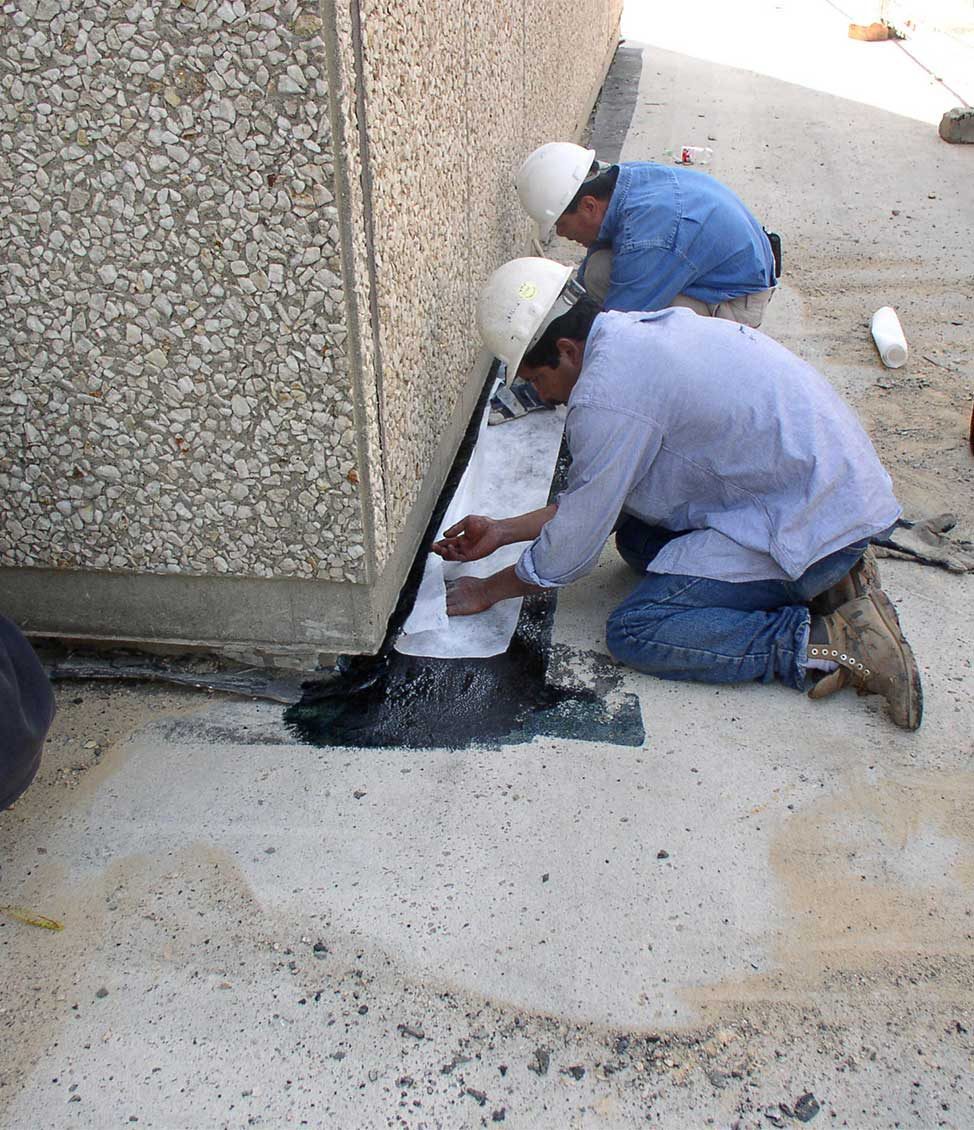 Construction workers performing waterproofing treatments