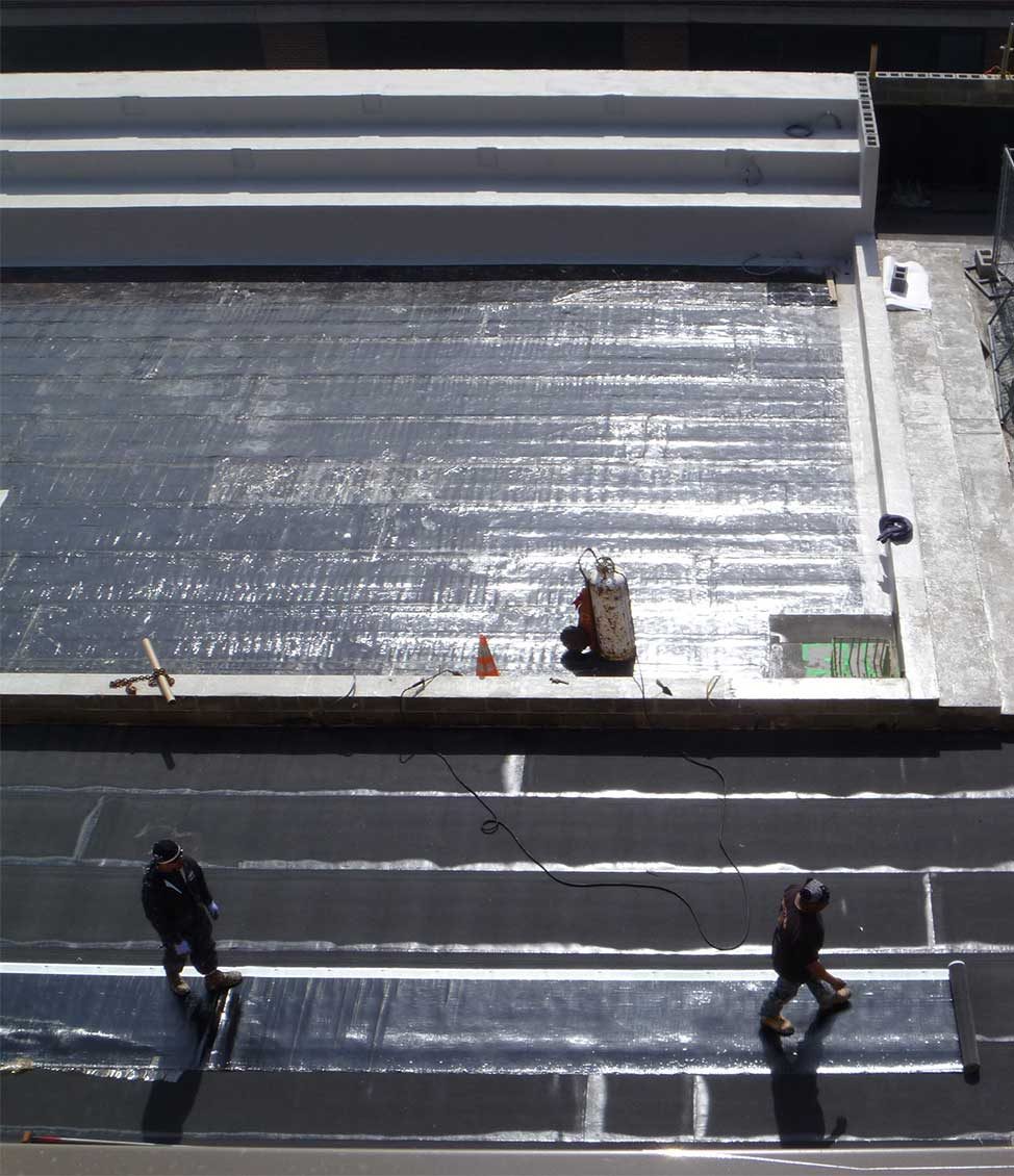 Construction workers performing waterproofing treatments