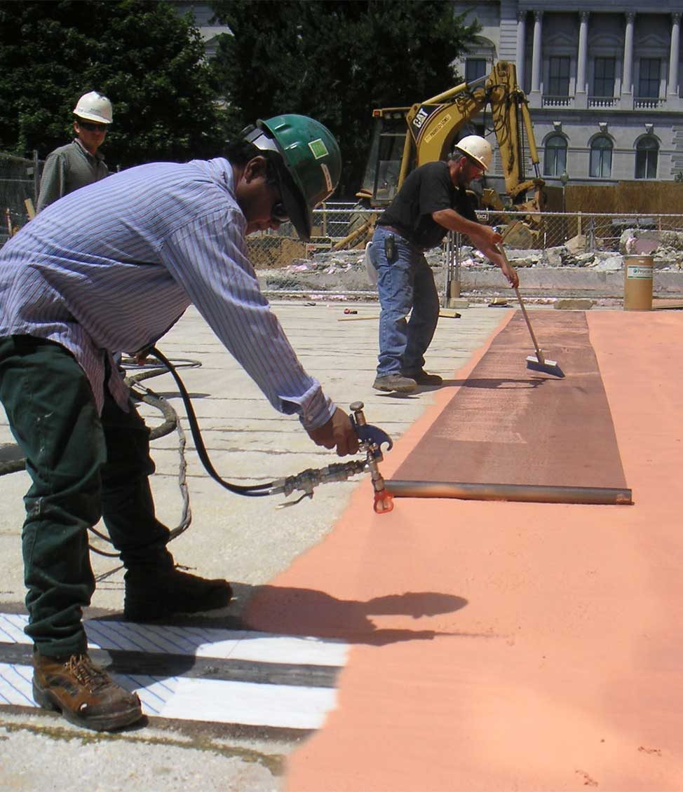 Construction workers performing waterproofing treatments