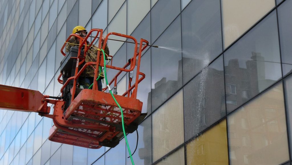 Construction worker spraying the window with water