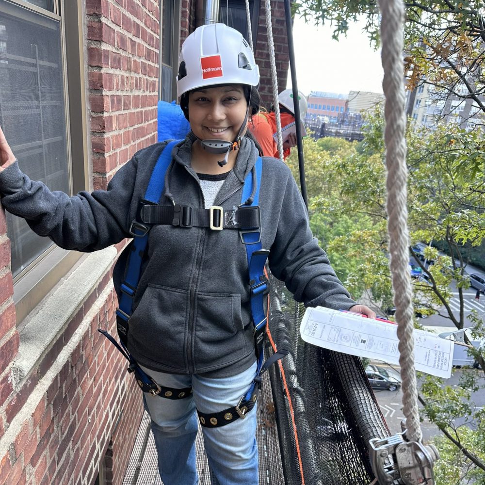 An architect wearing a hard had and harness on swing staging