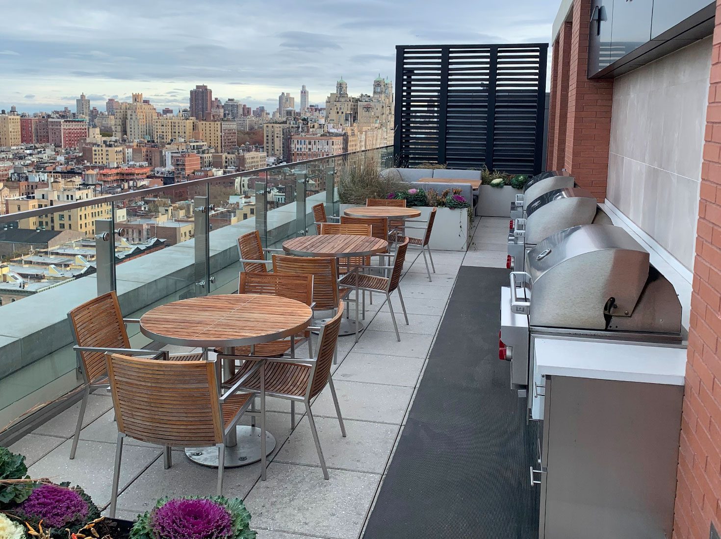 A rooftop with tables, chairs, and grills that overlooks New York City