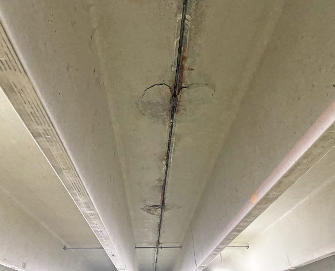 Spalled concrete on an overhead garage deck ready to fall.