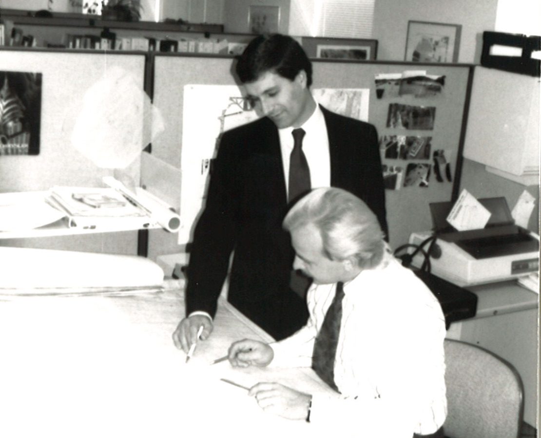 Russell Sanders and coworker at a drafting table in a black-and-white image