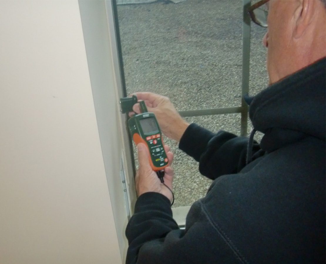 Architect Russell Sanders uses a moisture meter to investigate water infiltration