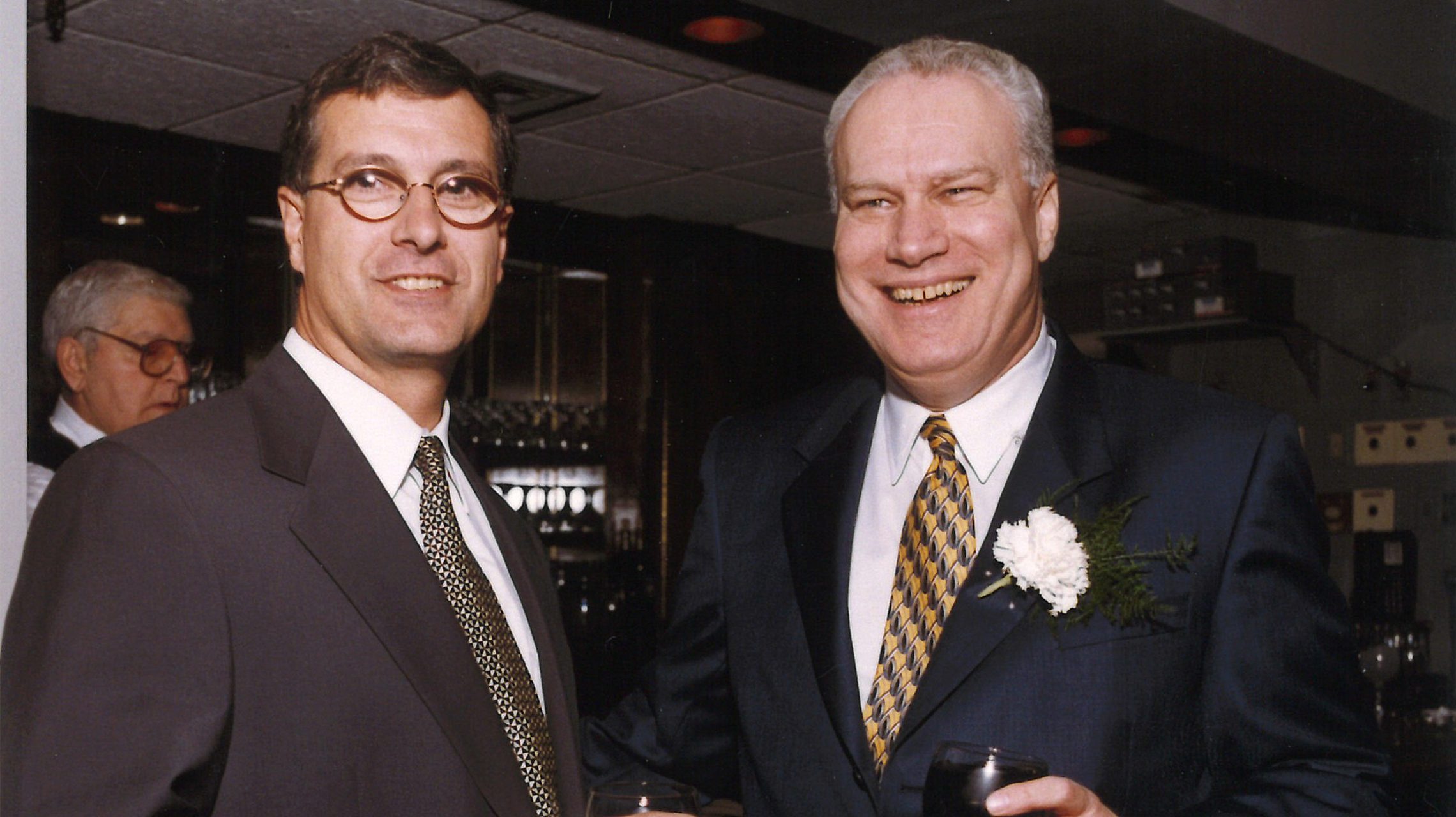 Architects Russ Sanders and John Hoffmann holding drinks at a company event in 1999