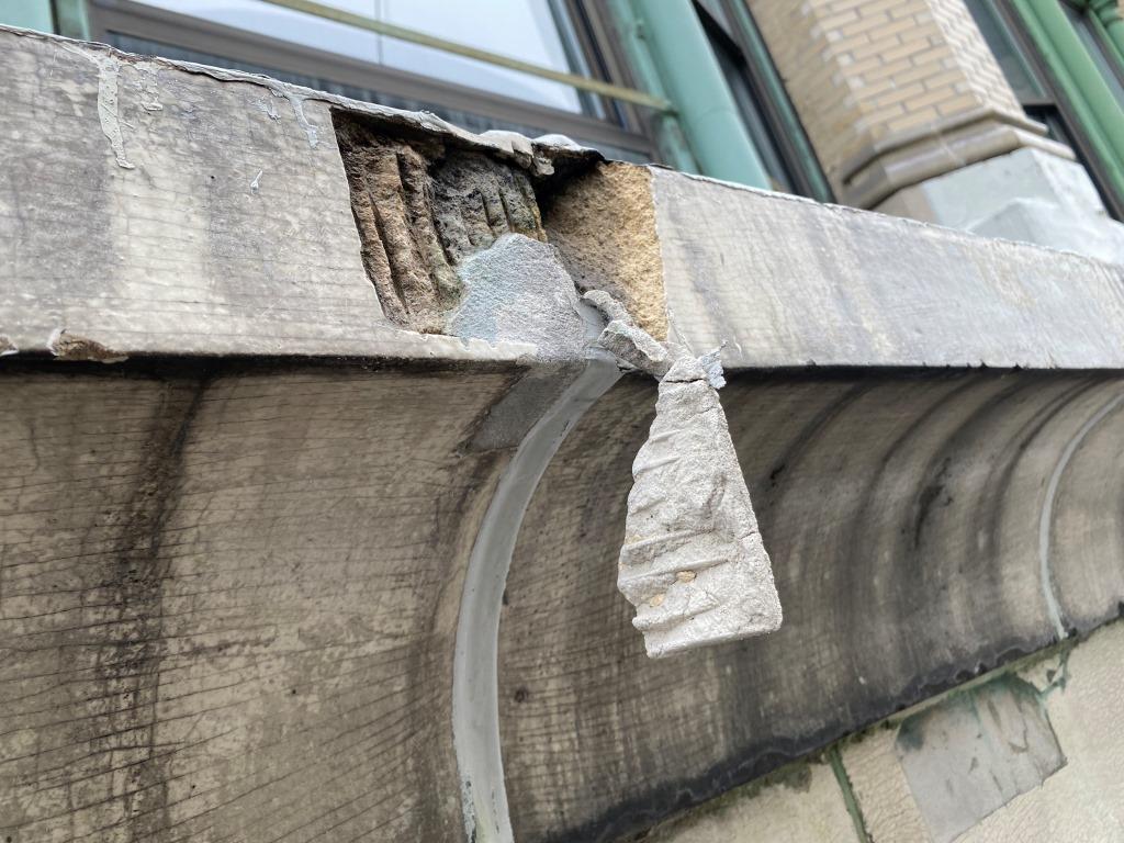 Spalled concrete dangling from a balcony ledge